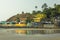 Bright yellow hotels on a hill with palm trees next to a wet sandy beach