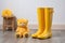 bright yellow kids rubber boots next to a fluffy teddy bear on a wooden floor