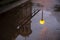 A bright yellow lantern, part of the temple and openwork railing are reflected in a rain puddle