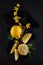 Bright yellow lemons, slices, rustic food photography on dark slate plate kitchen table