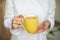 Bright yellow mug of tea with lemon. Girl holds a yellow mug with lemon. hand, shirt, fruit, vitamins, health, morning