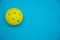 Bright yellow pickleball or whiffle ball on a solid bright blue flat lay background symbolizing sports and activity with copy