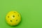 Bright yellow pickleball or whiffle ball on a solid bright green flat lay background symbolizing sports and activity with copy