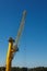 Bright yellow portal crane against blue sky, working in a harbour, vertical shot