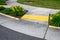 Bright yellow sidewalk guides on a corner crossing, with yellow daylilies planted on either side of the entrance