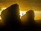 Bright yellow sun on the sea stacks with silhouette of a person standing on the top of a rock