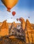 Bright yellow sunrise with colourful balloons floating just above cave homes in Cappodocia