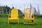 Bright Yellow Weathered Adirondack Chairs in the Grass in front of a Vineyard
