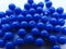 Brightly blue round beads for needlework are randomly scattered over a white background