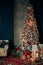 Brightly christmas tree in a room with red carpet with lots of gifts under it. New year holidays
