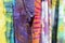 Brightly colored boho tie dyed garments hanging together - background - selective focus