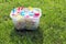 Brightly colored clothespins in a bucket on green grass in sunshine