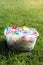 Brightly colored clothespins in a bucket on green grass in sunshine