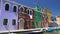 Brightly colored houses and boats at mooring points along canal on Burano island