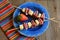 Brightly colored plate with fruit, sausage and cheese on wood background