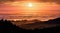 Brightly colored sunset in the Santa Cruz mountains, layered hills and valleys visible in the foreground and sea of clouds in the