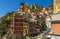 Brightly coloured buildings tumble down the hillside towards the small harbour in the Cinque Terre village of Riomaggiore, Italy
