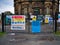 Brightly coloured construction site safety and social distancing signage on the gates of a closed United Utilities site.