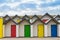 Brightly coloured front doors of four modern beach huts
