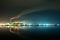 Brightly illuminated coal power plant high pipes with black smoke moving upwards polluting atmosphere at night with reflections of