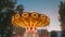Brightly illuminated rotating high speed carousel merry-go-round. Summer evening night in city amusement park