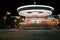 Brightly illuminated traditional carousel at night city street