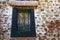 A brightly painted rock wall surrounds a decaying window with bars.