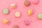 Brignt macarons for sweet break on pink background top view pattern