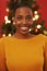 Brimming with festive cheer. an attractive young woman standing in front of a Christmas tree.