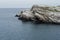 Brink of shore of wild little island with smooth light rocks and green moss in calm blue Arctic Ocean in sunny day, horizon.