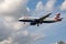 British Airways airliner soaring through a blue sky with fluffy white clouds in London, UK.