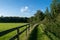 British footpath between the farmlands separated by woodden fence, hiking path through english coutryside land