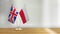 British and Polish flag pair on a desk over defocused background