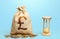 British pound sterling money bag and hourglass. Profitability and return on investment. Time for paying taxes. Pension savings.