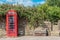 British red telephone booth by ancient rock wall with vines growing over both in village with style into pasture to the side