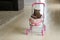 British Shorthair cat laying in colourful baby stroller indoors. Playful domestic cat sitting in a trolley inside