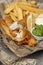 British Traditional crispy Fish and chips with mashed peas, tartar sauce on newspaper.