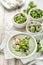 Broad bean soup with fresh mint and feta cheese in a white bowl on a wooden table.