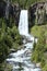 Broad waterfall and river surrounded by trees.