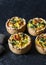 Broccoli cheddar mini savory pies on dark background, top view. Delicious appetizers, snack,