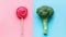 Broccoli and lollipop on a blue-pink split background. Healthy versus junk food. Diet concept. Generative AI