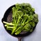 Broccolini fresh organic broccoli florets green vegetable baby broccoli, olive oil, sesame seeds in cast iron pan, vegan raw