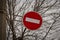 Brohibiting road sign brick set against bare tree branches as a symbol of restrictions in life