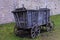 The broken ancient medieval rural wood cart or wagon on the green grass on the background of the castle or fortress wall