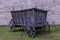 The broken ancient medieval rural wood cart or wagon on the green grass on the background of the castle or fortress wall