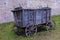 The broken ancient medieval rural wood cart or wagon on the green grass on the background of the castle or fortress wall