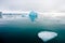 Broken Arctic ice floes float with a glacier in the distance