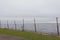 Broken barbed wire fence with a heart, with sea and coast in the background