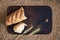 Broken bread and ears on a kitchen board against a background of wheat grains