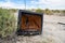 A broken, busted old CRT TV set sits abandoned and rotting in the desert of California